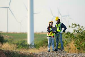 Engineer and worker discussing on a wind turbine farm with blueprints photo