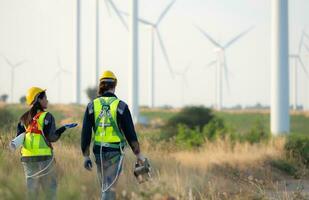 Engineer and worker discussing on a wind turbine farm with blueprints photo