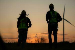 Silhouette of Engineer in charge of wind energy against a background of wind turbines. photo