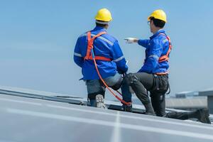 ambos de técnicos es instalando solar paneles en el techo de el almacén a cambio solar energía dentro eléctrico energía para utilizar en fábricas. foto