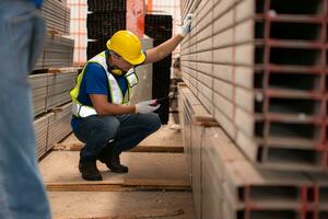 Warehouse worker in hard hats and helmets stand in the warehouse to count and inspect the steel in the warehouse. photo