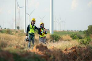 Engineer and worker discussing on a wind turbine farm with blueprints photo