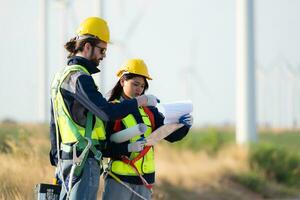 Engineer and worker discussing on a wind turbine farm with blueprints photo