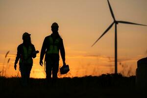 Silhouette of Engineer in charge of wind energy against a background of wind turbines. photo