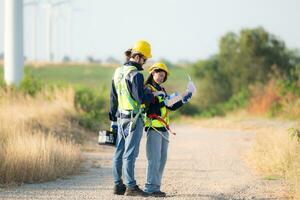 Engineer and worker discussing on a wind turbine farm with blueprints photo