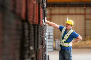 Portrait of a male worker wearing a safety vest and helmet standing on a steels pallet due to back pain from working in a factory lifting heavy things. photo