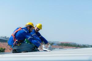 Both of technicians is installing solar panels on the roof of the warehouse to change solar energy into electrical energy for use in factories. photo