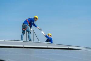 A young technician intern working on solar panels is fear of heights with senior engineers who are always helping out photo
