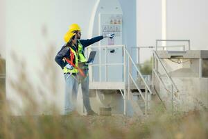 Engineer and worker discussing on a wind turbine farm with laptop photo