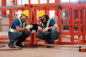 Portrait of two workers using digital tablet sit in front of the red steel structure photo