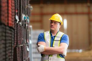 retrato de un construcción trabajador en pie con brazos cruzado en frente de aceros material pared foto