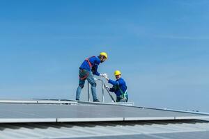 A young technician intern working on solar panels is fear of heights with senior engineers who are always helping out photo