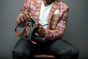 Unrecognizable man sitting on chair with retro camera inside a studio photo