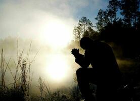 hombre Orando en el brumoso bosque foto