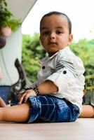 Baby boy at home balcony. Bright portrait of happy child sitting on the table. Little 1 year old boy during the day light at house balcony. photo