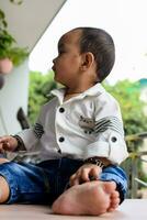 Baby boy at home balcony. Bright portrait of happy child sitting on the table. Little 1 year old boy during the day light at house balcony. photo