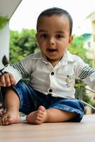 Baby boy at home balcony. Bright portrait of happy child sitting on the table. Little 1 year old boy during the day light at house balcony. photo