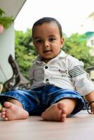 Baby boy at home balcony. Bright portrait of happy child sitting on the table. Little 1 year old boy during the day light at house balcony. photo