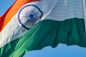 India flag flying high at Connaught Place with pride in blue sky, India flag fluttering, Indian Flag on Independence Day and Republic Day of India, tilt up shot, Waving Indian flag, Har Ghar Tiranga photo