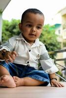 Baby boy at home balcony. Bright portrait of happy child sitting on the table. Little 1 year old boy during the day light at house balcony. photo