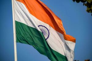 India flag flying high at Connaught Place with pride in blue sky, India flag fluttering, Indian Flag on Independence Day and Republic Day of India, tilt up shot, Waving Indian flag, Har Ghar Tiranga photo