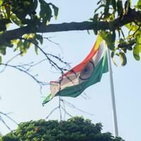 India flag flying high at Connaught Place with pride in blue sky, India flag fluttering, Indian Flag on Independence Day and Republic Day of India, tilt up shot, Waving Indian flag, Har Ghar Tiranga photo