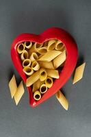 fresh pasta penne rigate in a red heart shaped container photo