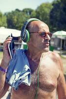 Mature modern man listens to music with headphones photo