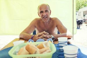 sonriente maduro hombre mientras esperando para su esposa para almuerzo foto