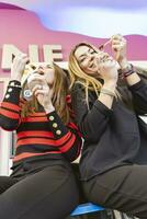 dos hermosa hembra amigos comiendo hielo crema en el lavandería habitación foto