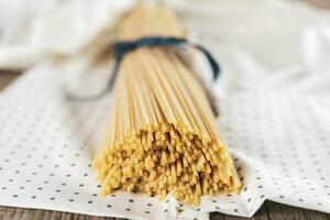 grupo de sin cocer italiano espaguetis pasta atado juntos por azul seda cinta foto