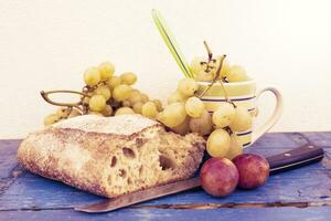 bread and grapes on white wall background photo