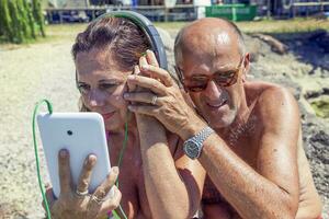 modern mature couple listening to music with headphones photo