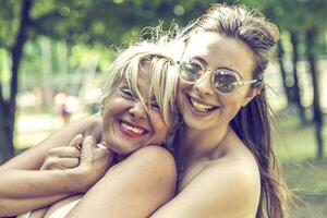 mother and daughter while posing hugged together in swimsuit photo