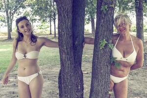 mother and daughter while posing hugged together in swimsuit photo