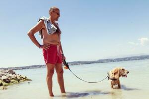 mature man relaxing with his dog in the fresh water photo