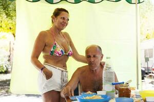 sonriente maduro hombre preparando almuerzo con su esposa foto