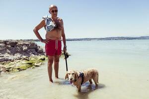 mature man relaxing with his dog in the fresh water photo