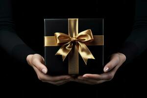 AI generated Black Friday sale. Young woman hand holding black gift box with gold bow on black background. Black Friday sale, promotion, discount, shopping concept. photo
