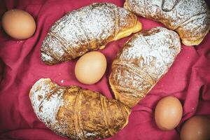 recién horneado croissants y cuatro huevos con en polvo azúcar en un cesta Listo para desayuno foto