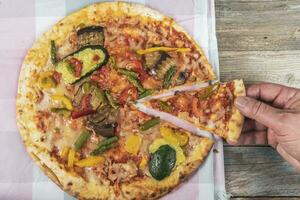 Tasty grilled vegetable pizza cooked with ingredients on wooden background. photo