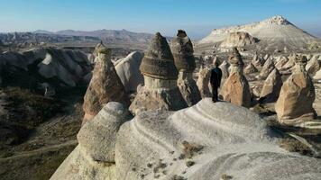 Aerial drone view of a person admiring the natural beauty of Pasabag Valley or Monks Valley and  Fairy Chimneys In Cappadocia, Turkey. Famous destination for hikers to explore the Rock Sites. video