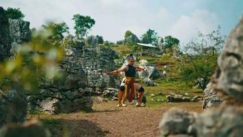 a female warrior is learning kung fu with her teacher who is holding a sword around a large rock video