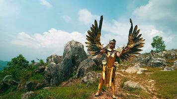 a warlord in a golden wing costume stands boldly and decisively on a cliff with white clouds video