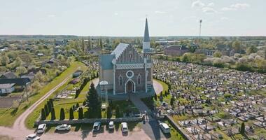 Antenne Aussicht und fliegen durch Über alt Ziegel Neo gotisch Tempel oder katholisch Kirche auf Friedhof im Landschaft video