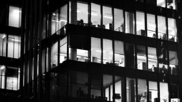 Pattern of office buildings windows illuminated at night. Glass architecture ,corporate building at night - business concept. Black and white. photo