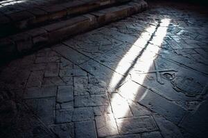 The light that enters through its small window on the floor. Sant Miquel del Fai monastery. Carved words on the stone. photo