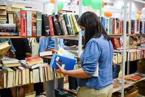 Delhi, India, September 09 2023 - Various age group people reading variety of Books on shelf inside a book-stall at Delhi International Book Fair, Selection of books on display in Annual Book Fair photo