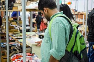 Delhi, India, September 09 2023 - Various age group people reading variety of Books on shelf inside a book-stall at Delhi International Book Fair, Selection of books on display in Annual Book Fair photo