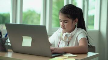 criança menina aprende lições, pensativo criança fazendo dever de casa pensativamente olhando para uma computador portátil tela . controlo remoto Educação tecnologias e trabalho de casa. video